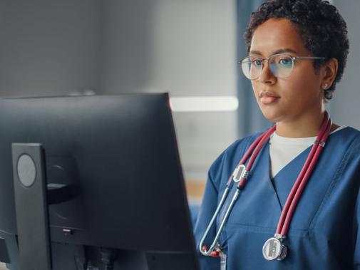 Junior doctor standing at computer in scrubs